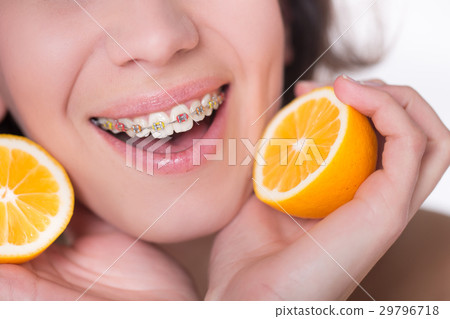 Girl with multi-colored braces tastes a lemon 29796718