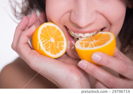 Girl with multi-colored braces tastes a lemon 29796719