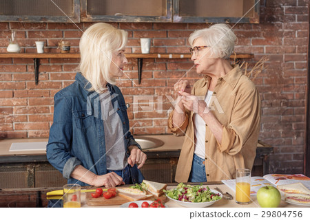 Joyful mature women cooking in kitchen Joyful mature women cooking in kitchen 29804756