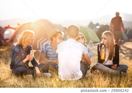 Teenagers sitting on the ground in front of tents Teenagers sitting on the ground in front of tents 29808242