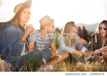 Teenagers sitting on the ground in front of tents Teenagers sitting on the ground in front of tents 29808248