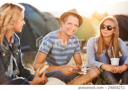 Teenagers sitting on the ground in front of tents Teenagers sitting on the ground in front of tents 29808251