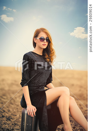 photo of beautiful young woman sitting on suitcase 29809014