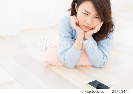 Thinking of a woman watching a smartphone in a room Thinking of a woman watching a smartphone in a room 29815444