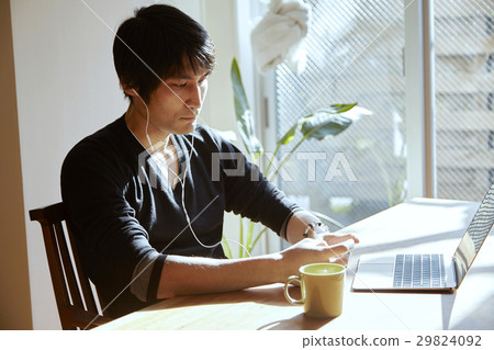 一個在陽光充足的房間裡聽音樂的人。放鬆在度假,餐桌的場面。 一個在陽光充足的房間裡聽音樂的人。放鬆在度假,餐桌的場面。 29824092