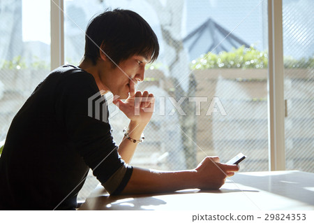 A smartphone and a man. A scenes to relax in a sunny room. 29824353