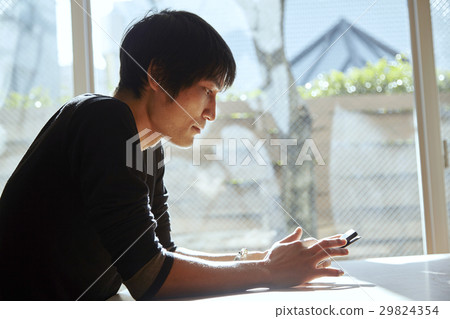 A smartphone and a man. A scenes to relax in a sunny room. A smartphone and a man. A scenes to relax in a sunny room. 29824354