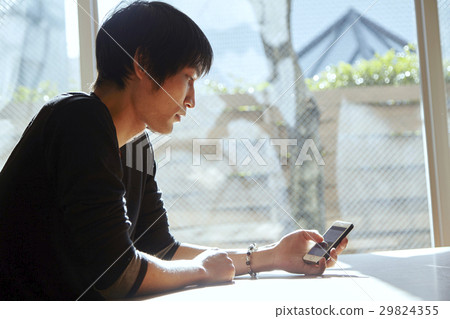 A smartphone and a man. A scenes to relax in a sunny room. 29824355