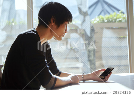 A smartphone and a man. A scenes to relax in a sunny room. 29824356