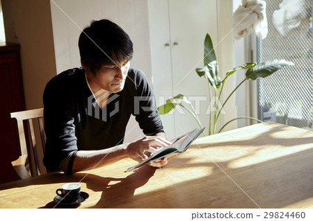 A man who reads in a sunny room. Scenes relaxing on holiday, sunny dining. 29824460