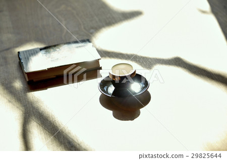 The shade of trees falling impressively on books, coffee cups and dining tables. Imagine a mystery novel The shade of trees falling impressively on books, coffee cups and dining tables. Imagine a mystery novel 29825644