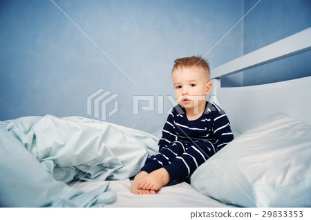 Sleepy boy sitting in bed 29833353