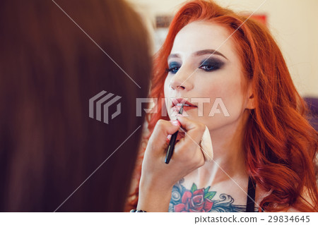 Make-up artist does makeup to the red-haired girl 29834645