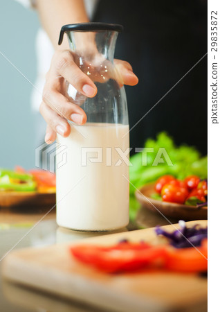 Woman hand holding milk bottle with vegetables. Woman hand holding milk bottle with vegetables. 29835872