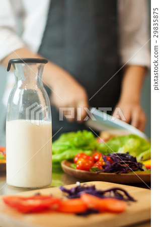 Milk in bottle with woman cooking and vegetables. Milk in bottle with woman cooking and vegetables. 29835875