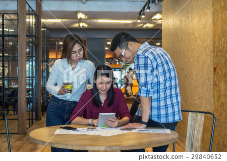 Group Of Asian Business people with casual suit Meeting in looking at the tablet action In the modern coffee shop, business group concept Group Of Asian Business people with casual suit Meeting in looking at the tablet action In the modern coffee shop, business group concept 29840652