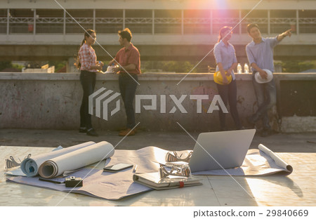 Construction equipment such as blueprint, Safety glasses and technology laptop over the photo blurred of engineers working with sun ray and lens flare background, industrial concept, worm color tone Construction equipment such as blueprint, Safety glasses and technology laptop over the photo blurred of engineers working with sun ray and lens flare background, industrial concept, worm color tone 29840669