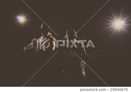 Musician Duo band playing a Trumpet and singing a song and playing the guitar on black background with spot light and lens flare, musical concept Musician Duo band playing a Trumpet and singing a song and playing the guitar on black background with spot light and lens flare, musical concept 29840670