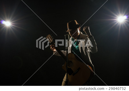 Asian Musician singing a song and playing the guitar which have a microphone on black background with spot light and lens flare, musical concept Asian Musician singing a song and playing the guitar which have a microphone on black background with spot light and lens flare, musical concept 29840732