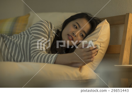 A young lady setting an alarm clock A young lady setting an alarm clock 29851443
