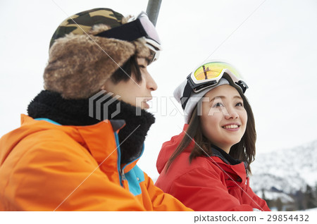 A couple riding a ski resort lift 29854432