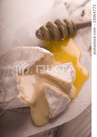 Brie cheese, slices, honey on parchment partial Brie cheese, slices, honey on parchment partial 29864772