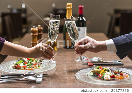 Two people toasting at a restaurant 29877856