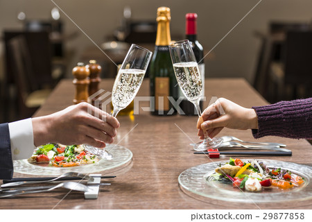Two people toasting at a restaurant 29877858