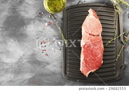 Piece of raw meat of beef on a grill with pepper 29882553