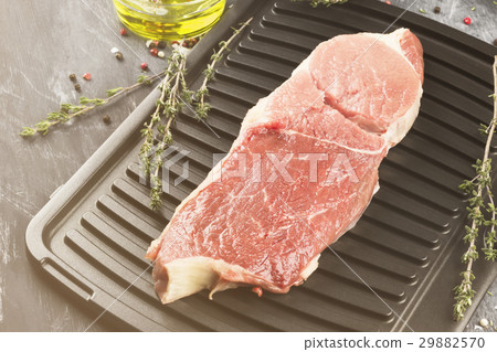 Piece of raw meat of beef on a grill with pepper Piece of raw meat of beef on a grill with pepper 29882570