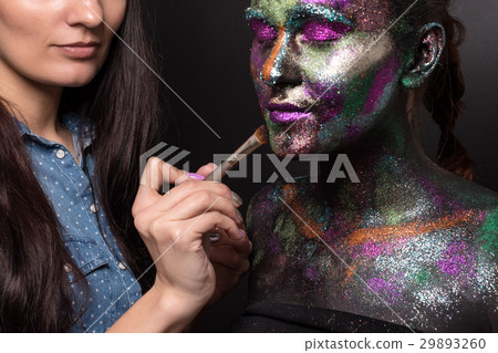 Makeup artist applies black paint and colourful 29893260