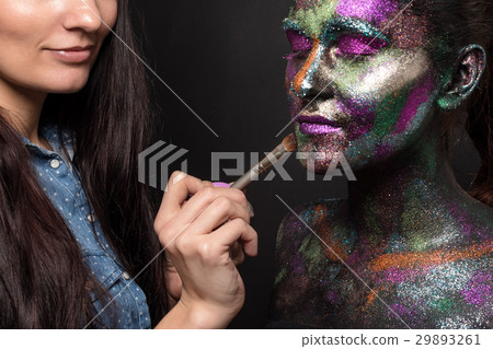 Makeup artist applies black paint and colourful 29893261