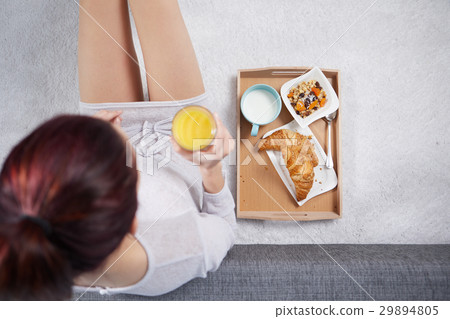 The girl in the morning eats a croissant and drink juice. top v The girl in the morning eats a croissant and drink juice. top v 29894805