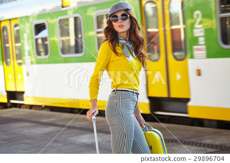 Beautiful young woman with suitcase is waiting a train Beautiful young woman with suitcase is waiting a train 29896704