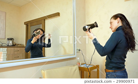 Pretty woman drying long hair in make-up room 29900971