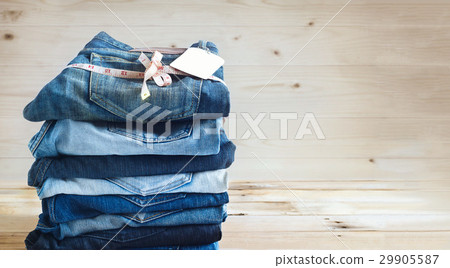 Jeans with measure and tag label stacked on wooden 29905587