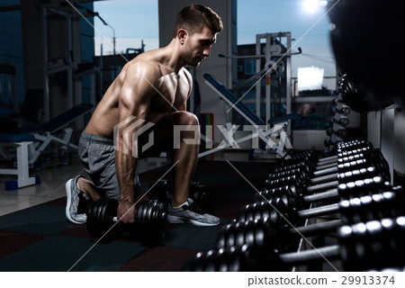 bodybuilder working out with bumbbells weights at 29913374