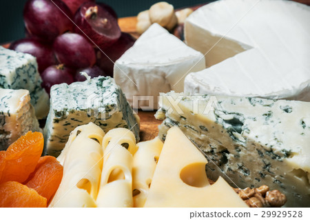 Assorted cheeses with grapes and nuts on a wooden Assorted cheeses with grapes and nuts on a wooden 29929528