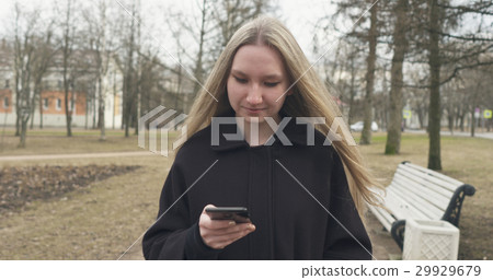 teen girl walking in town park and using teen girl walking in town park and using 29929679