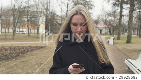 teen girl walking in town park and using 29929682