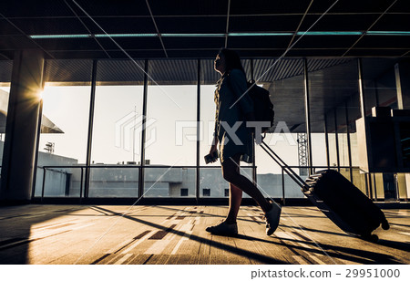 Silhouette of girl walking with luggage at airport 29951000