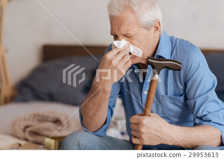 Moody aged man blowing his nose Moody aged man blowing his nose 29953613