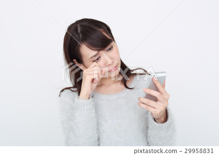 A woman crying at the screen of a smartphone 29958831