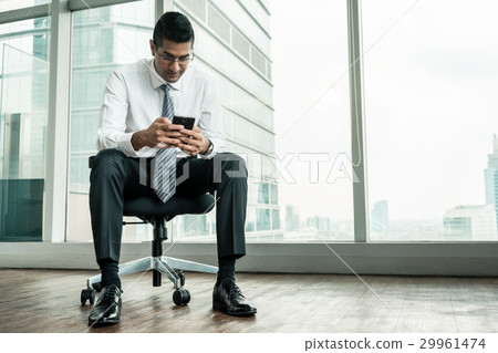 Businessman using a mobilephone while sitting down Businessman using a mobilephone while sitting down 29961474