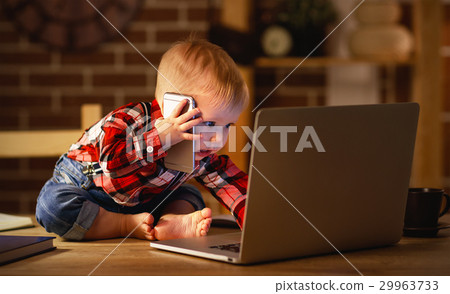 concept of baby boy working on computer and talking on phone 29963733