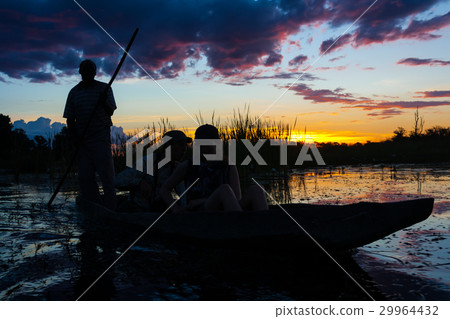 Kanu mit im Gegenlicht bei Daemmerung im Okawango 29964432