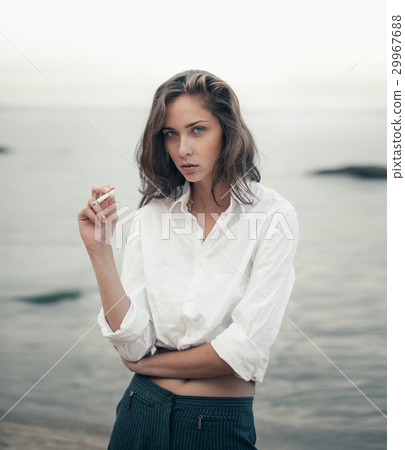 Cute woman smokes a cigarette on the beach 29967688