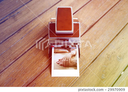 Vintage retro instant photo camera on the wooden table 29970909