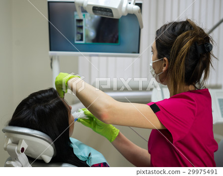 Dentist examining woman's teeth with camera 29975491