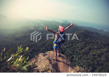 woman hiker open arms hiking on mountain peak 29976029